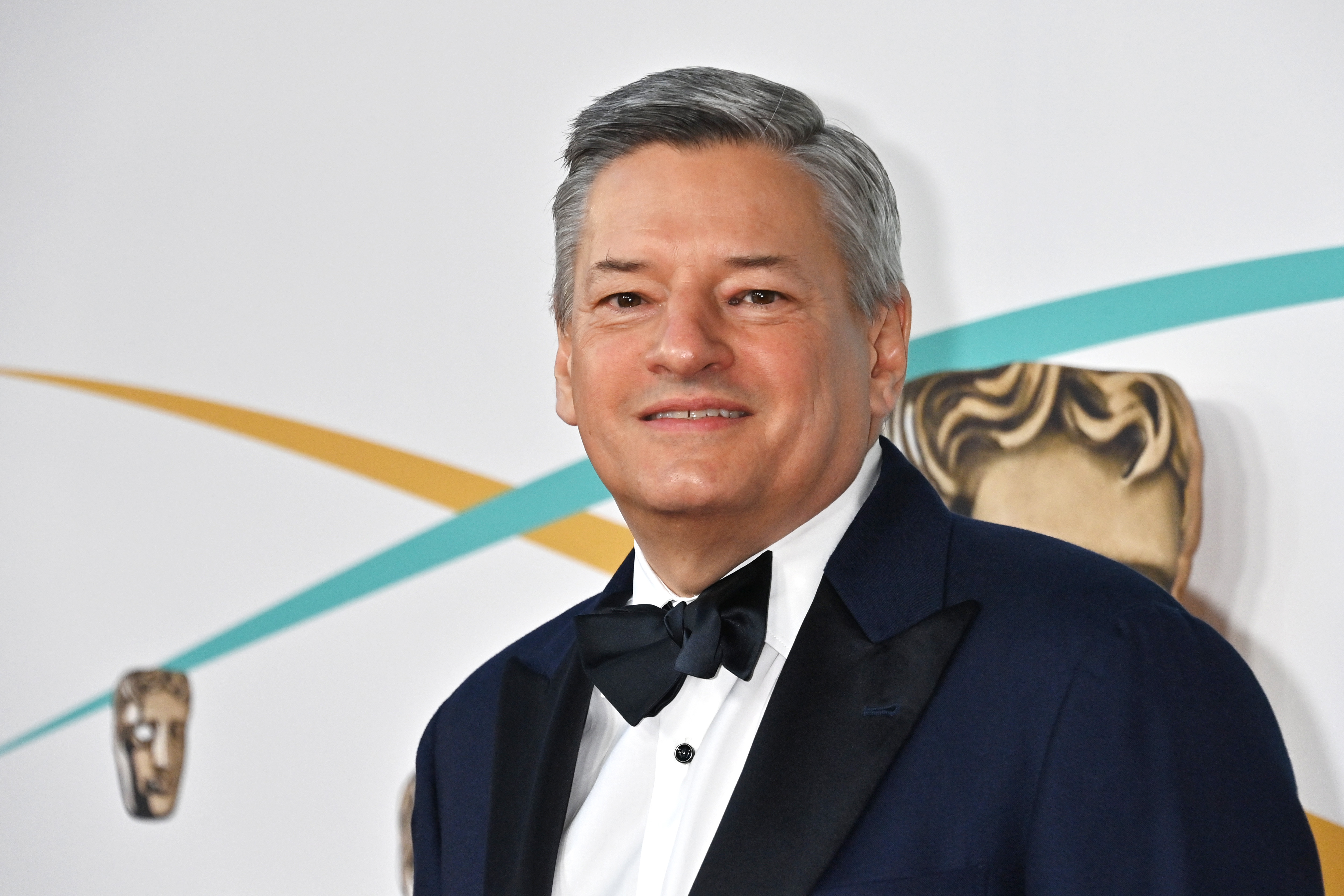 Ted Sarandos smiles wearing a suit.