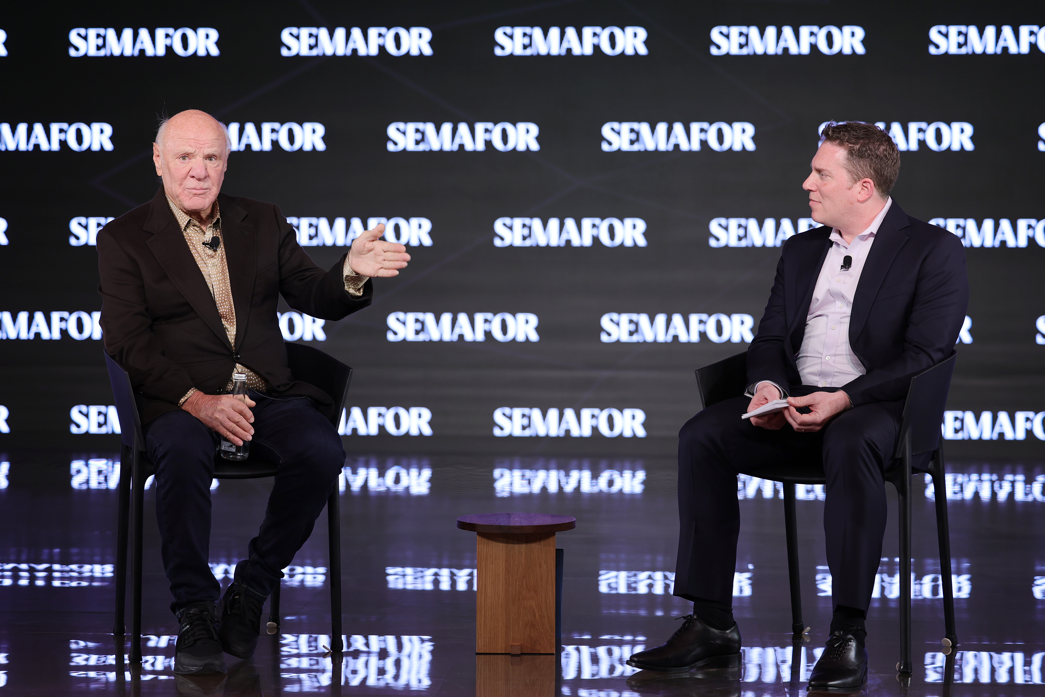 Barry Diller sits next to Ben Smith in front of a Semafor sign.