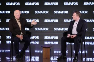 Barry Diller sits next to Ben Smith in front of a Semafor sign.