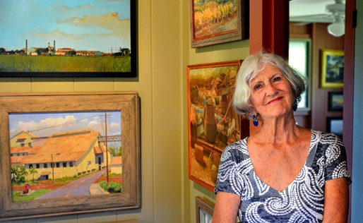 Woman stands in front of gallery wall filled with paintings