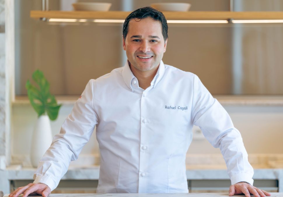man with brown hair in white chef shirt smiling at camera 