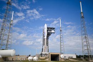 Photo of large white rocket standing on ground against blue sky