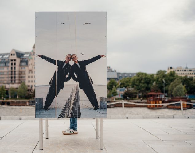 A sign of a man leaning against a mirror in a mostly empty outdoor space