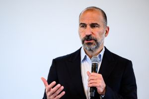 Man in black blazer and white button up speaks into microphone